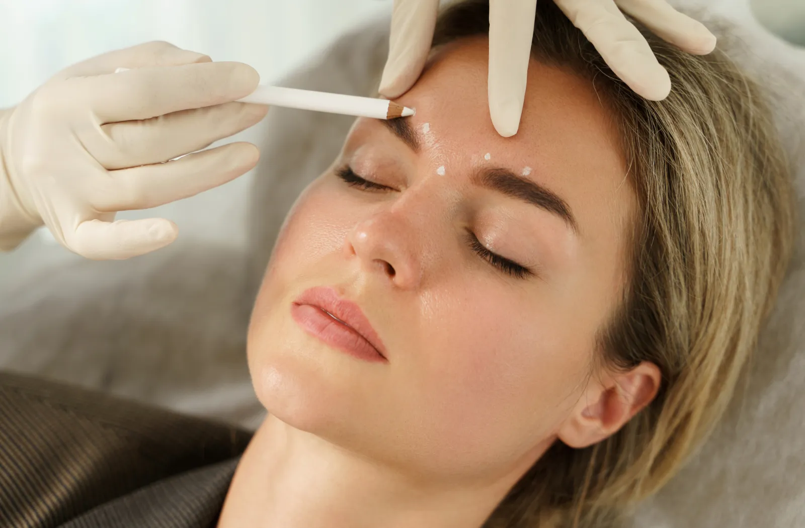 Patient receiving a cosmetic treatment on the forehead by a gloved practitioner.