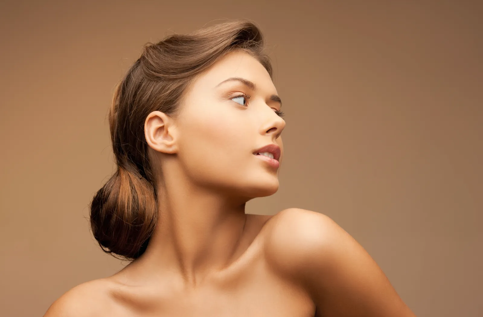 Young woman with natural beauty, showcasing a profile view against a neutral background.