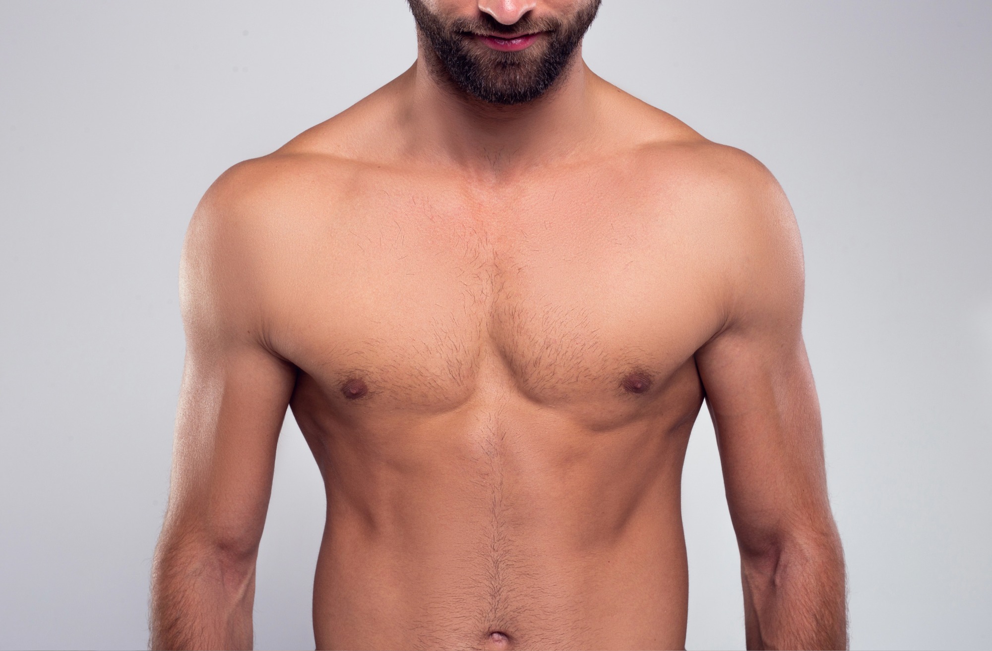 Close-up of a shirtless man’s upper torso showing chest, shoulders, and part of the face with a beard.