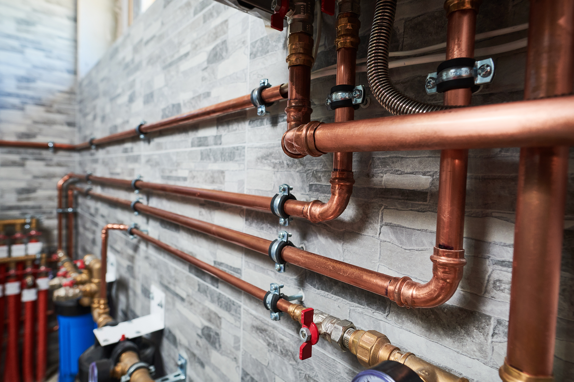A set of copper pipes ran along a tile wall
