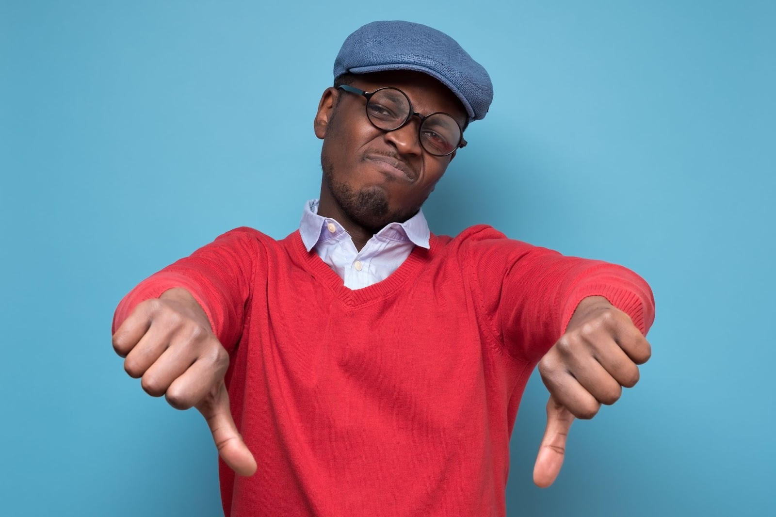 Choisir de déléguer sa production graphique auprès de freelances graphistes peut s'avérer être une mauvaise idée car il y a des conséquences à prendre en compte. Personne avec un pull rouge qui met en garde contre les inconvénients de faire appel à un graphiste freelance pour déléguer sa production de contenus visuels