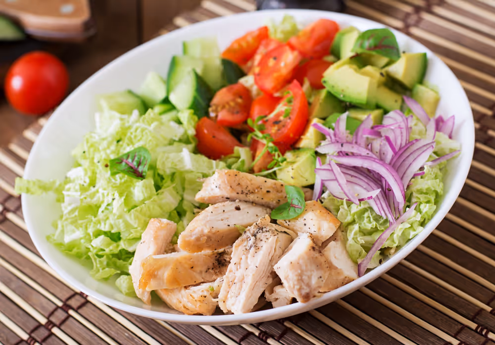 A bowl of salad with tomatoes, lettuce, and beans.