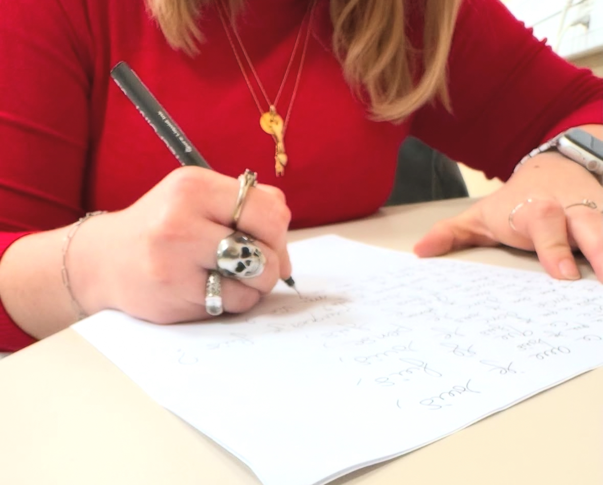 Lisa écrit et porte un pull rouge