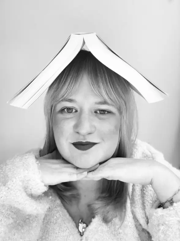 photo noir et blanc Lisa qui porte un livre sur la tête et mains sous le menton