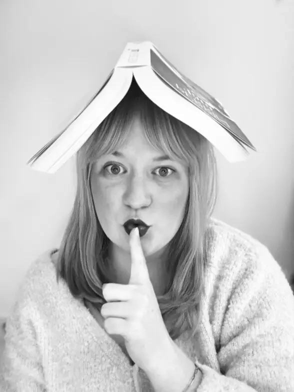 Photo noir et blanc Lisa avec un livre sur la tête et qui fait chut