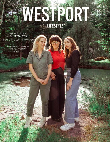 Cover of Westport Lifestyle, July 2025 issue, featuring the band I’m With Her standing in a lush, wooded area beside a pond. The three women are smiling and casually dressed, with dappled sunlight filtering through the trees. The headline highlights their summer performance at the Levitt Pavilion.