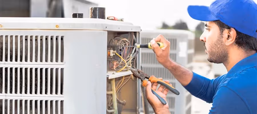 Technician Repairing commercial HVAC wearing blue cap