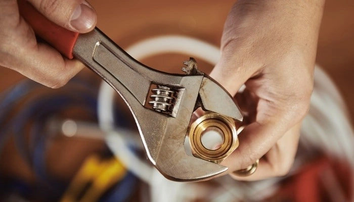 Hands tightening plumbing nut with wrench.
