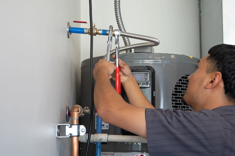 Man tightening pipes on water heater.