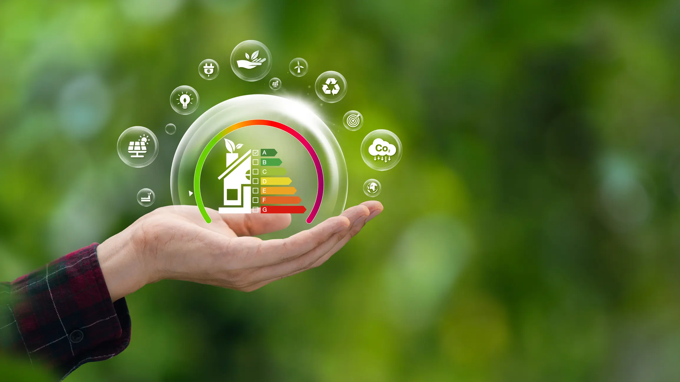 A hand holds a floating bubble with a house energy efficiency rating chart inside, surrounded by icons for solar power, wind energy, and carbon dioxide reduction, set against a green, natural background.