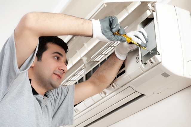 A professional servicing an indoor AC unit.