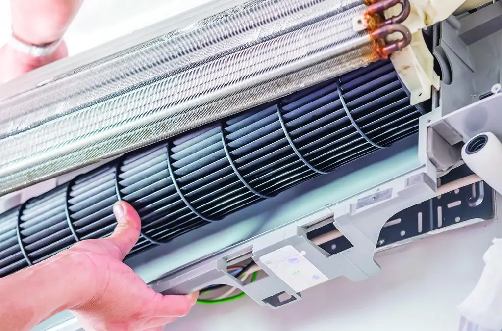 A hand holding a part of an AC unit.