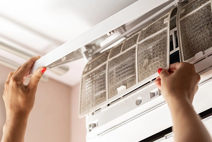 A person removing a very dirty AC filter.