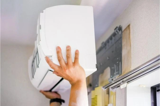 A worker replacing an indoor AC unit.