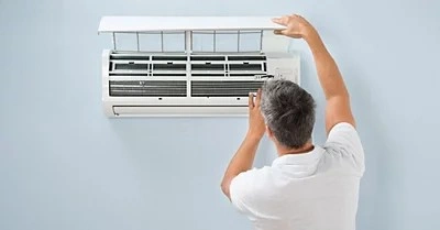 A person servicing an indoor mini split AC.