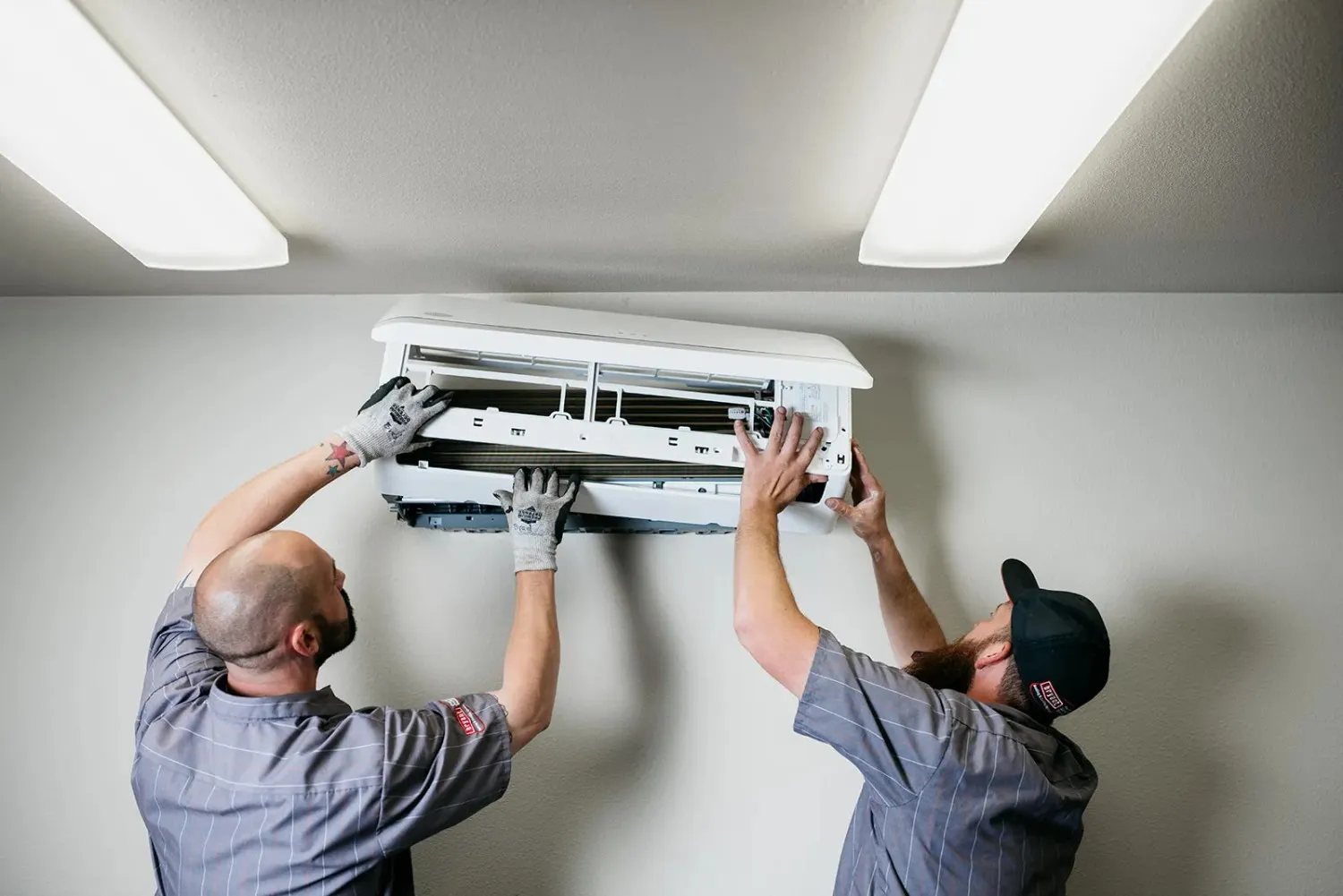 Two professionals replacing an indoor AC unit.