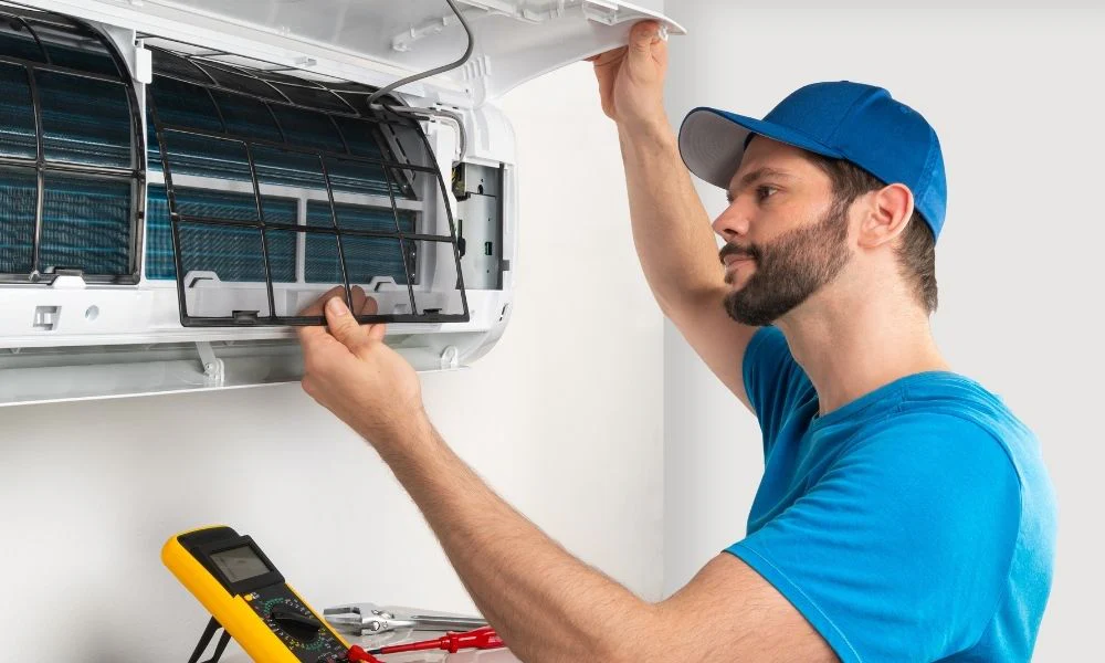 A worker cleaning an air conditioner.