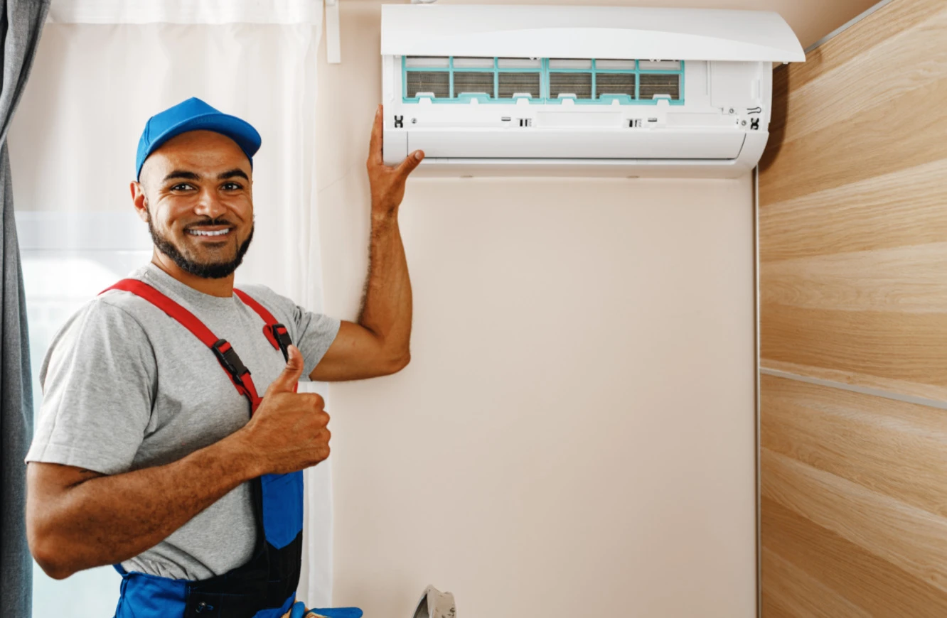 A worker giving thumbs up after cleaning an air conditioner.