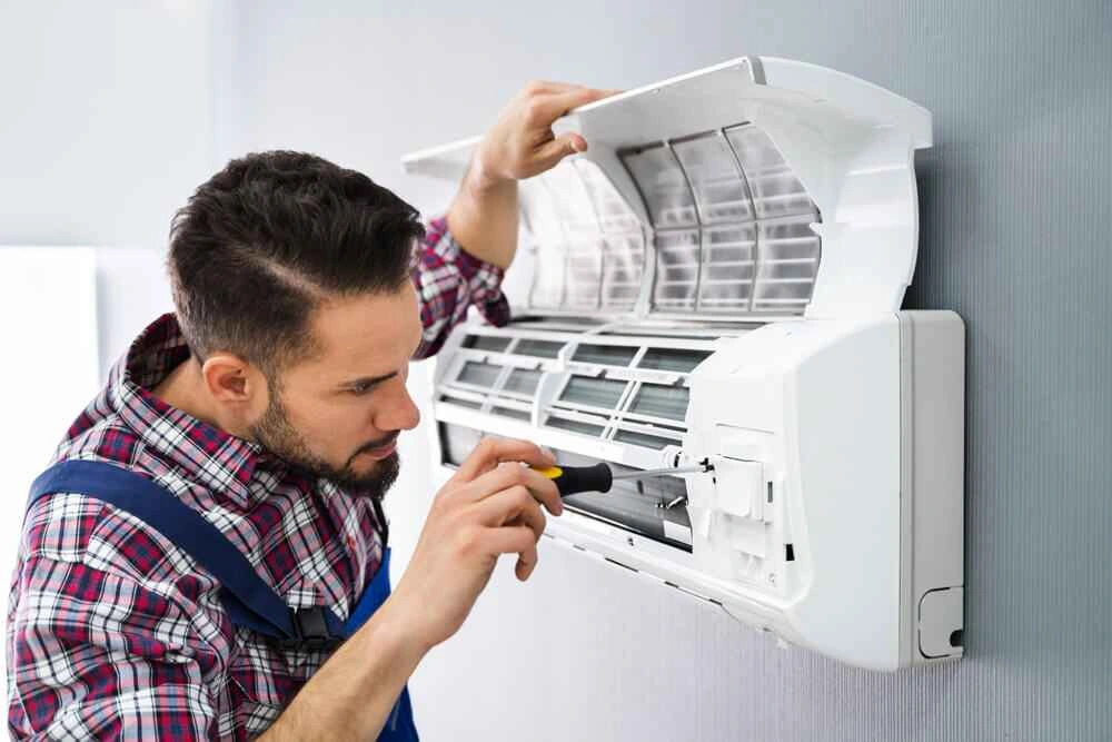 A worker repairing an air conditioner.