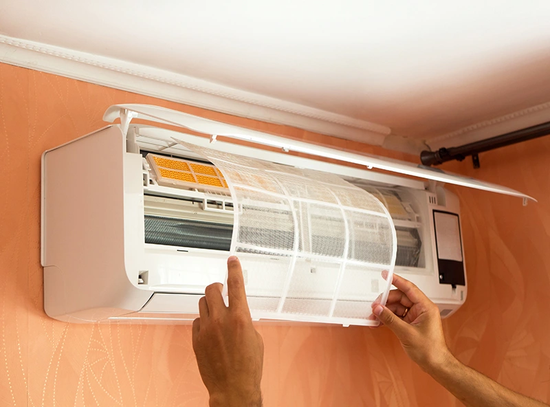 A person cleaning an air conditioner.