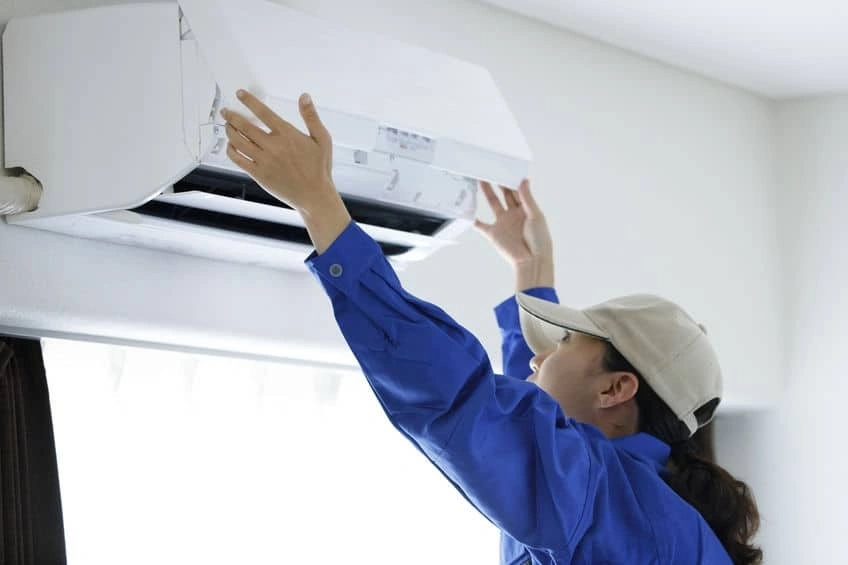 A worker servicing an indoor AC unit.