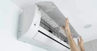 A person cleaning the filter of an AC unit.
