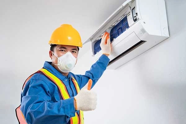 A worker doing AC repair, thumbs up.