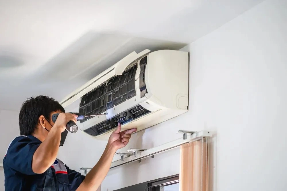 A repairman installing a wall-mounted AC unit.