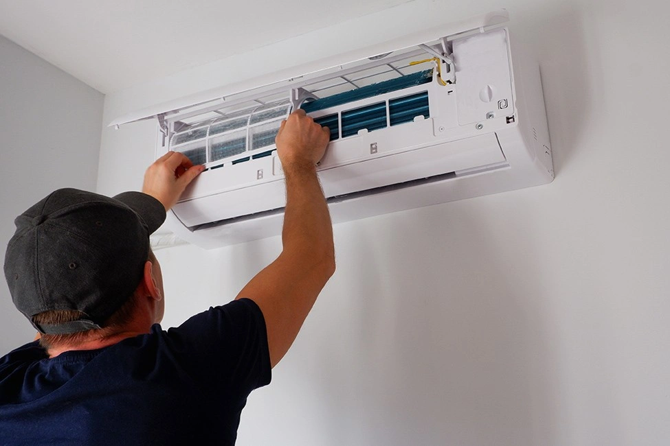 A man cleaning a mini-split AC filter.