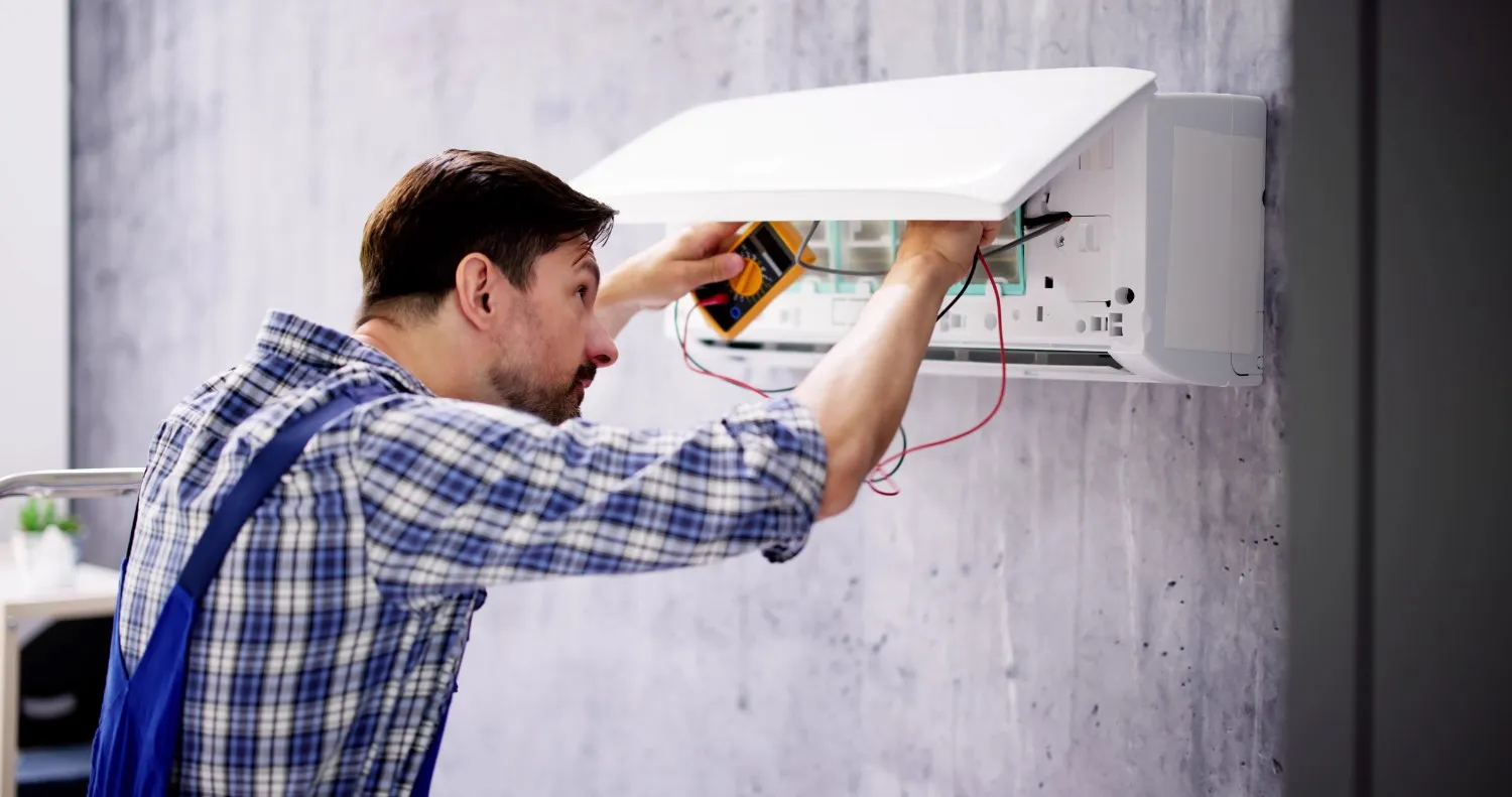 A person using a multimeter on an AC.