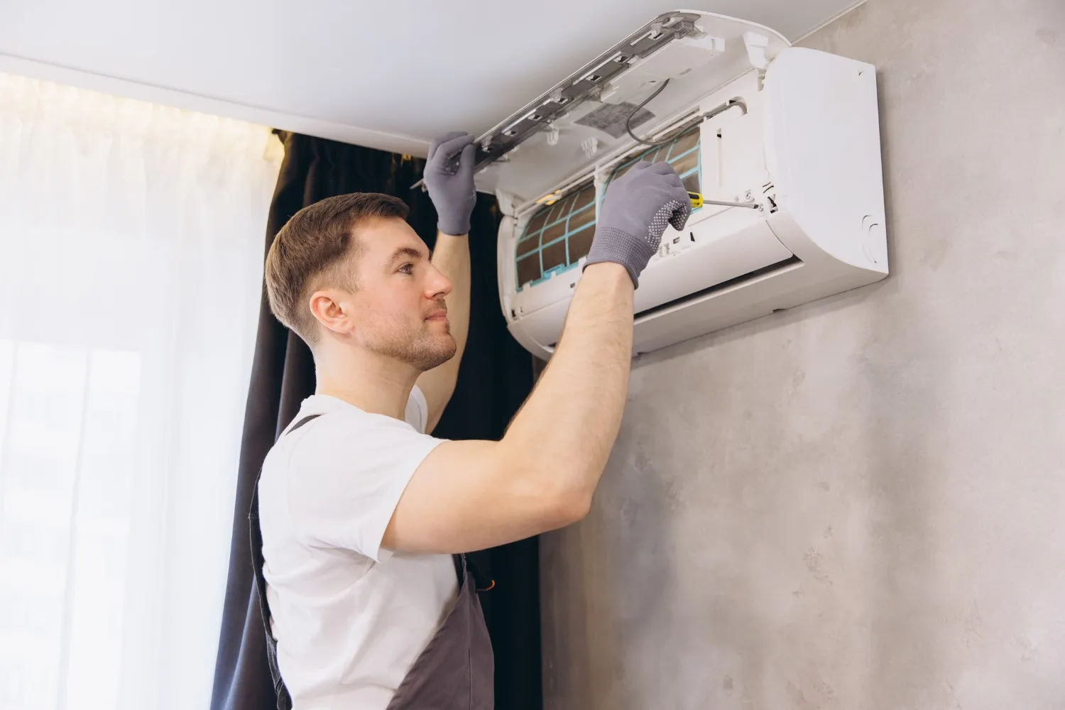 A repairman fixing a mini-split AC unit.