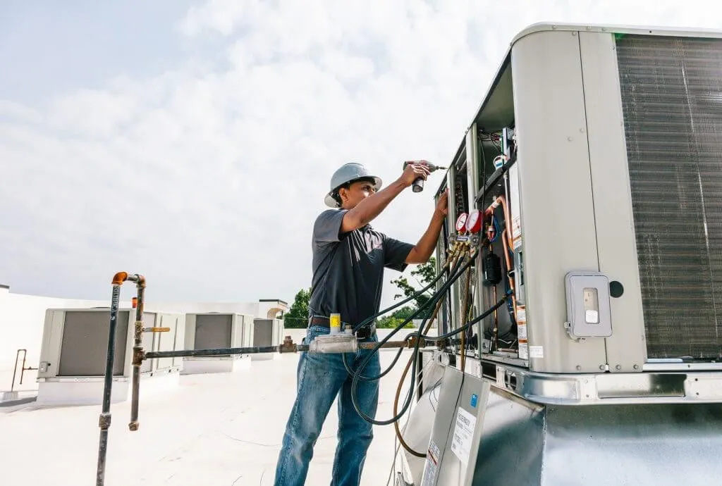 Technician servicing large rooftop HVAC unit.