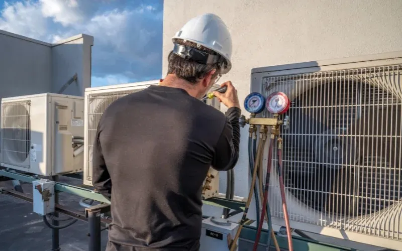 Technician checks gauges on commercial AC.