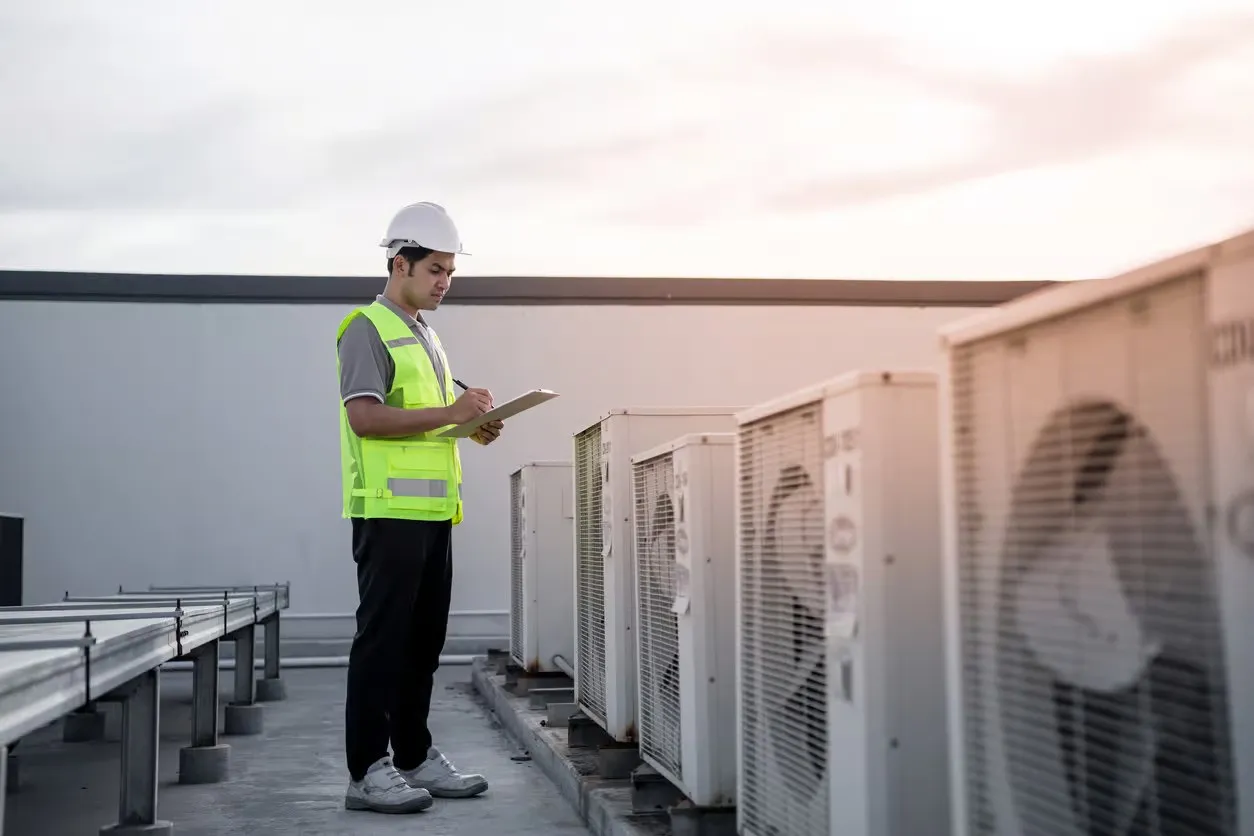 HVAC worker inspecting rooftop AC units.