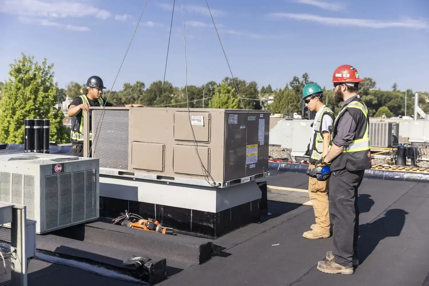 Workers craning large commercial AC unit.
