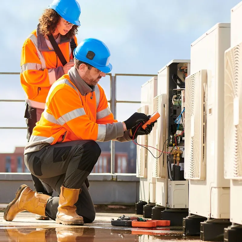 HVAC technicians testing electrical components on rooftop.