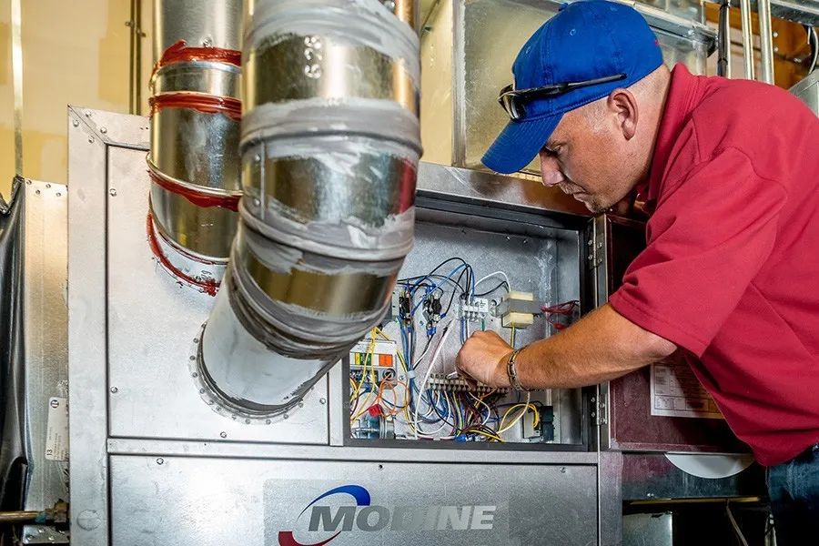 Technician checking wires on an HVAC unit.