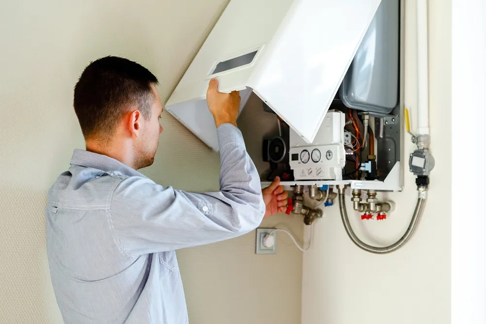 Man repairing wall-mounted residential heater.