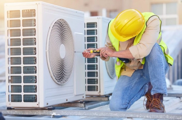 Two workers inspecting outdoor HVAC units.