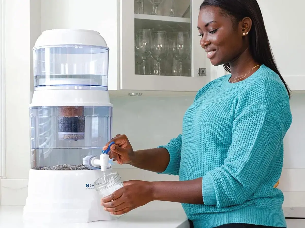 Woman dispensing water from gravity filter.