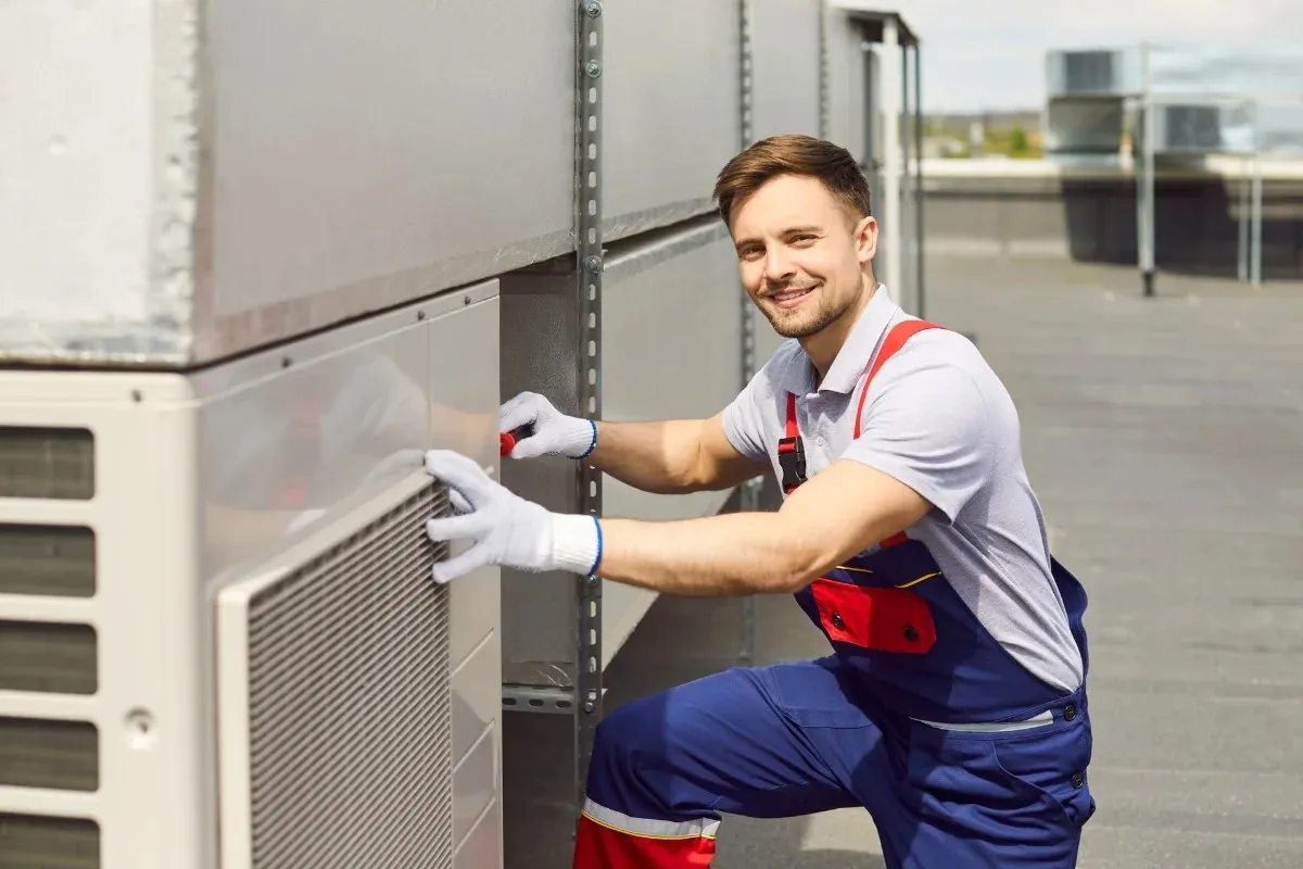 Smiling HVAC technician working on rooftop unit
