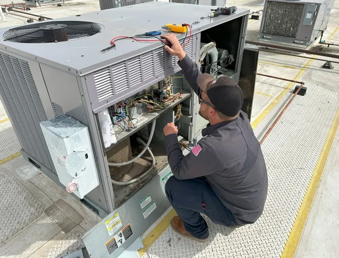 Technician repairs commercial rooftop HVAC unit