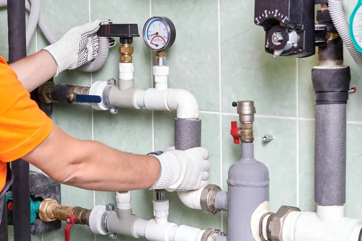 Plumber adjusts gauge on pipe system.