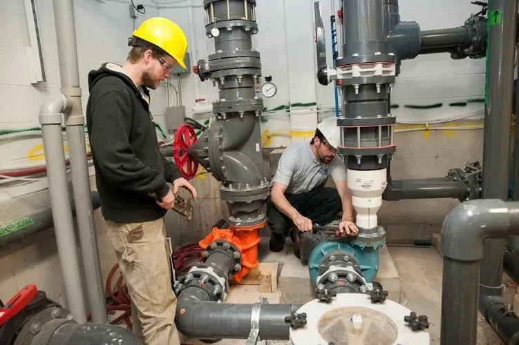 Two plumbers working on large pipes.