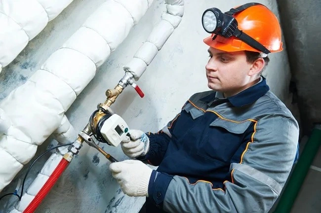 Technician in helmet repairs insulated pipe.