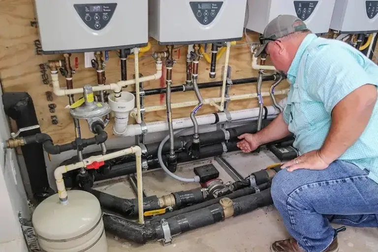 Man inspects complex water heater piping.