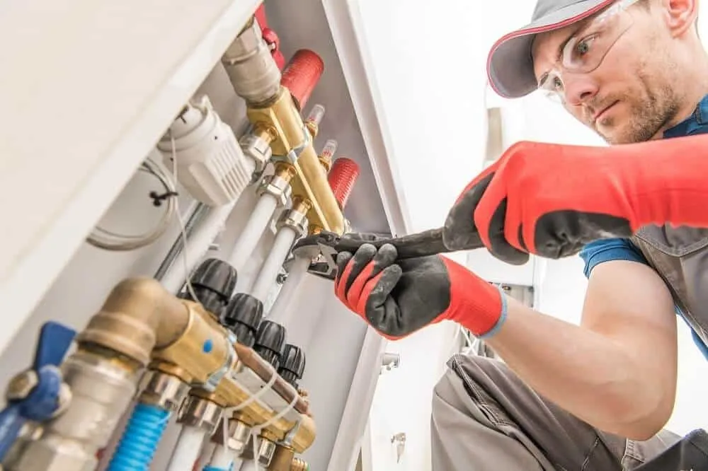 Plumber adjusts valves on water manifold.