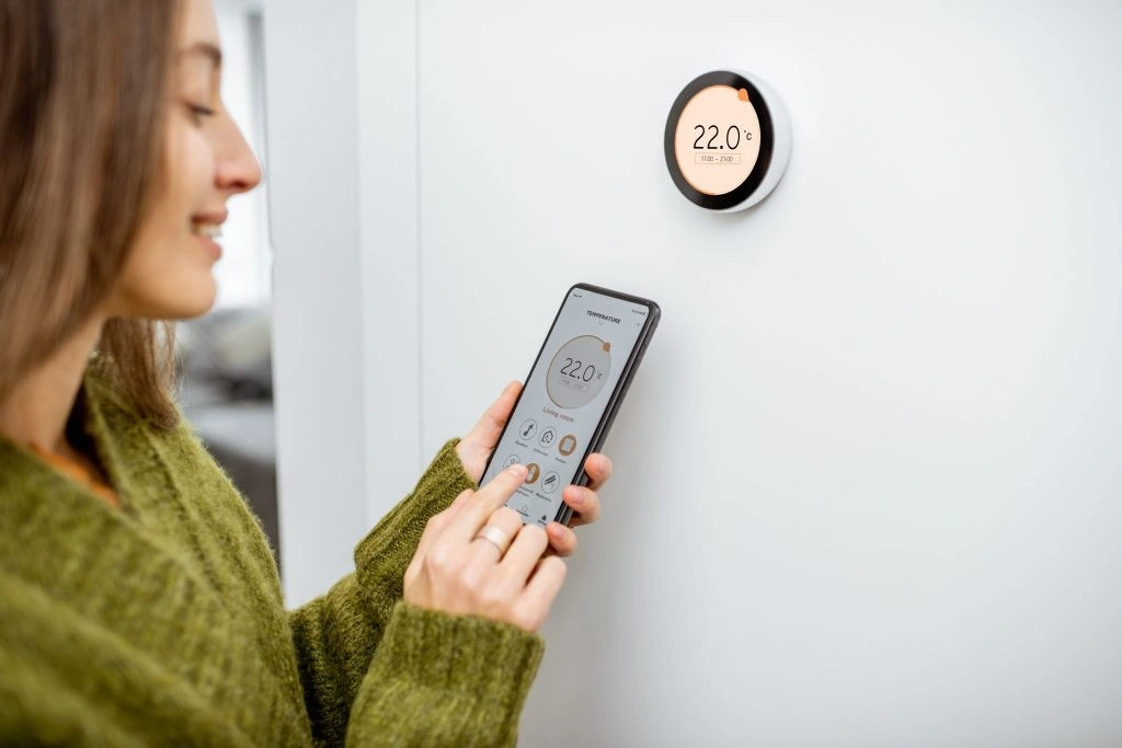 Woman adjusting thermostat with smartphone app.