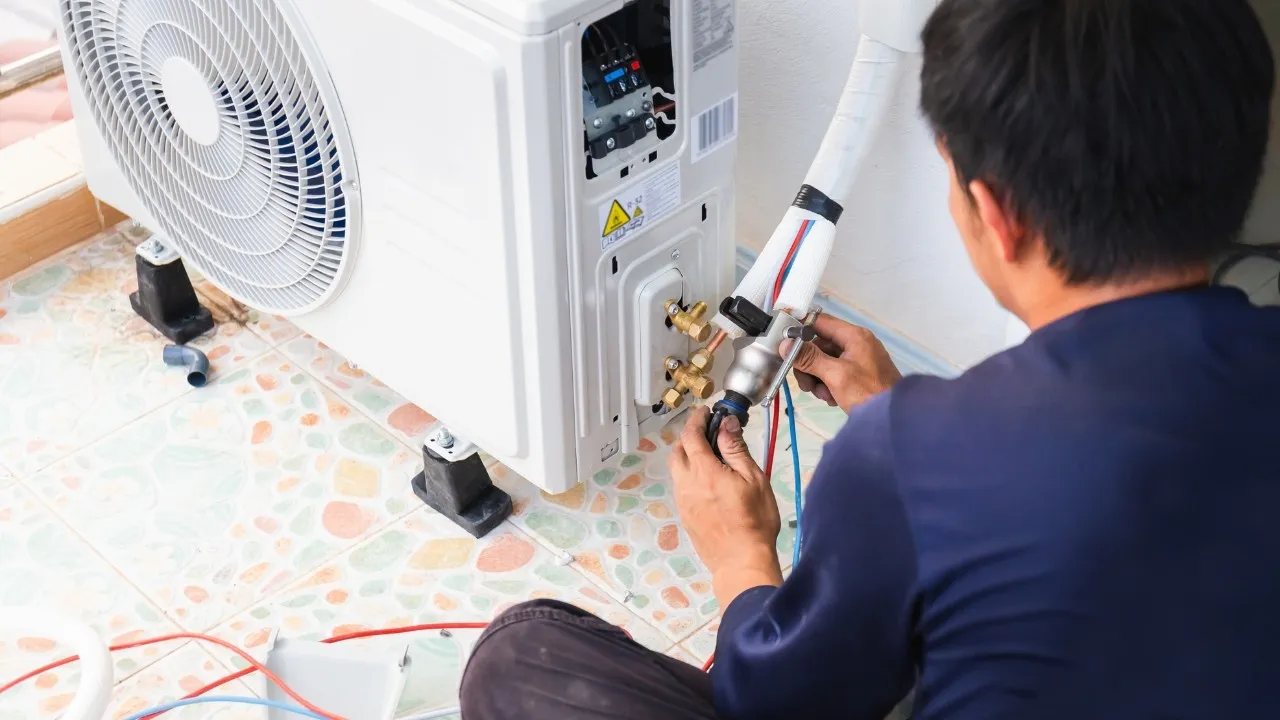 Technician connecting refrigerant lines to outdoor AC.