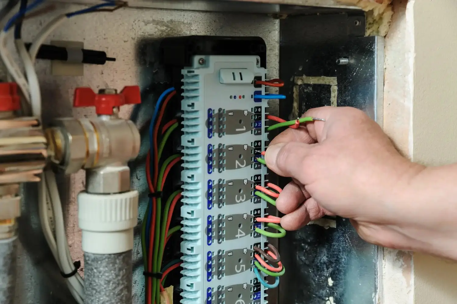 Hand wiring a terminal strip for a heating control system.